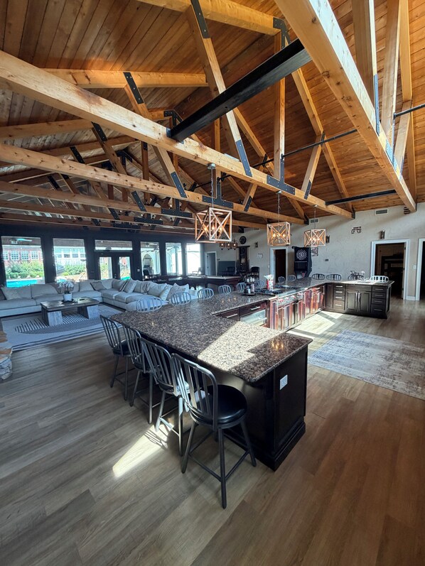 A spacious kitchen with a large island, wooden beams, and modern lighting fixtures.