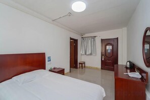 A hotel room with a bed, a desk, a chair, a mirror, and a door. - Lingshan Hotel (Shanghai)