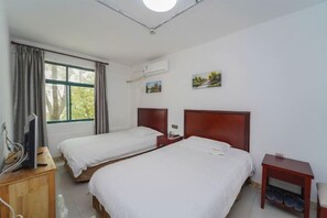 A hotel room with two beds, a wooden dresser, a television, and a window with curtains. - Lingshan Hotel (Shanghai)