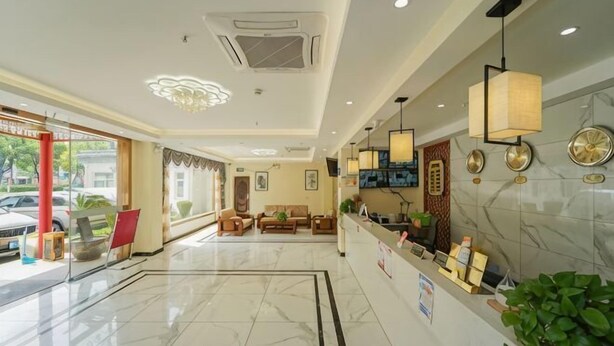 Un hall de hotel con mostrador de recepción, zona de estar y un amplio ventanal con vista a coches estacionados.