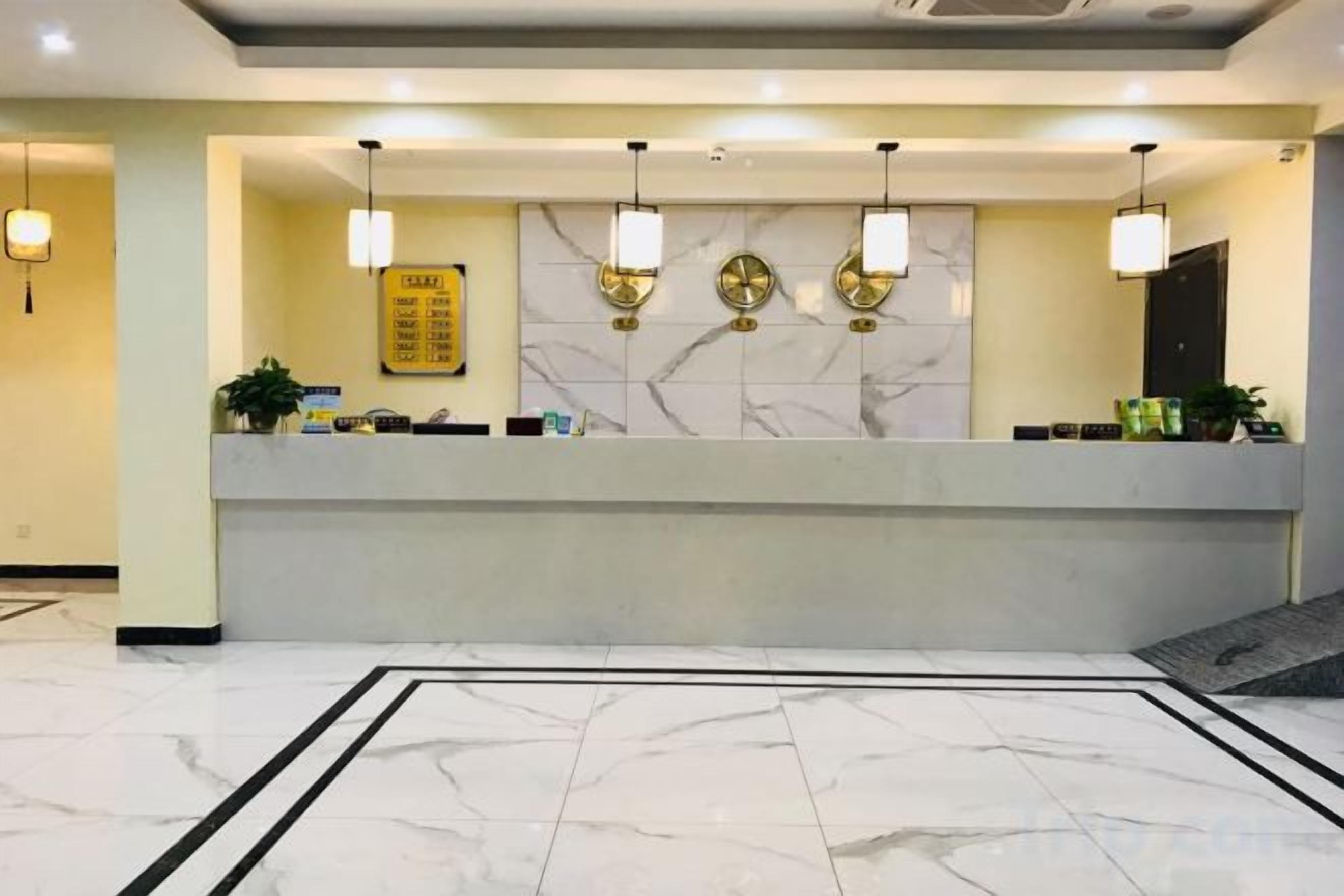 A hotel reception area with a marble floor, a reception desk, and wall-mounted light fixtures.
