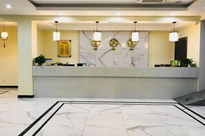 A hotel reception area with a marble floor, a reception desk, and wall-mounted light fixtures. - Lingshan Hotel (Shanghai)