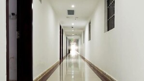 Un pasillo largo y estrecho con paredes blancas y un suelo de baldosas brillantes.