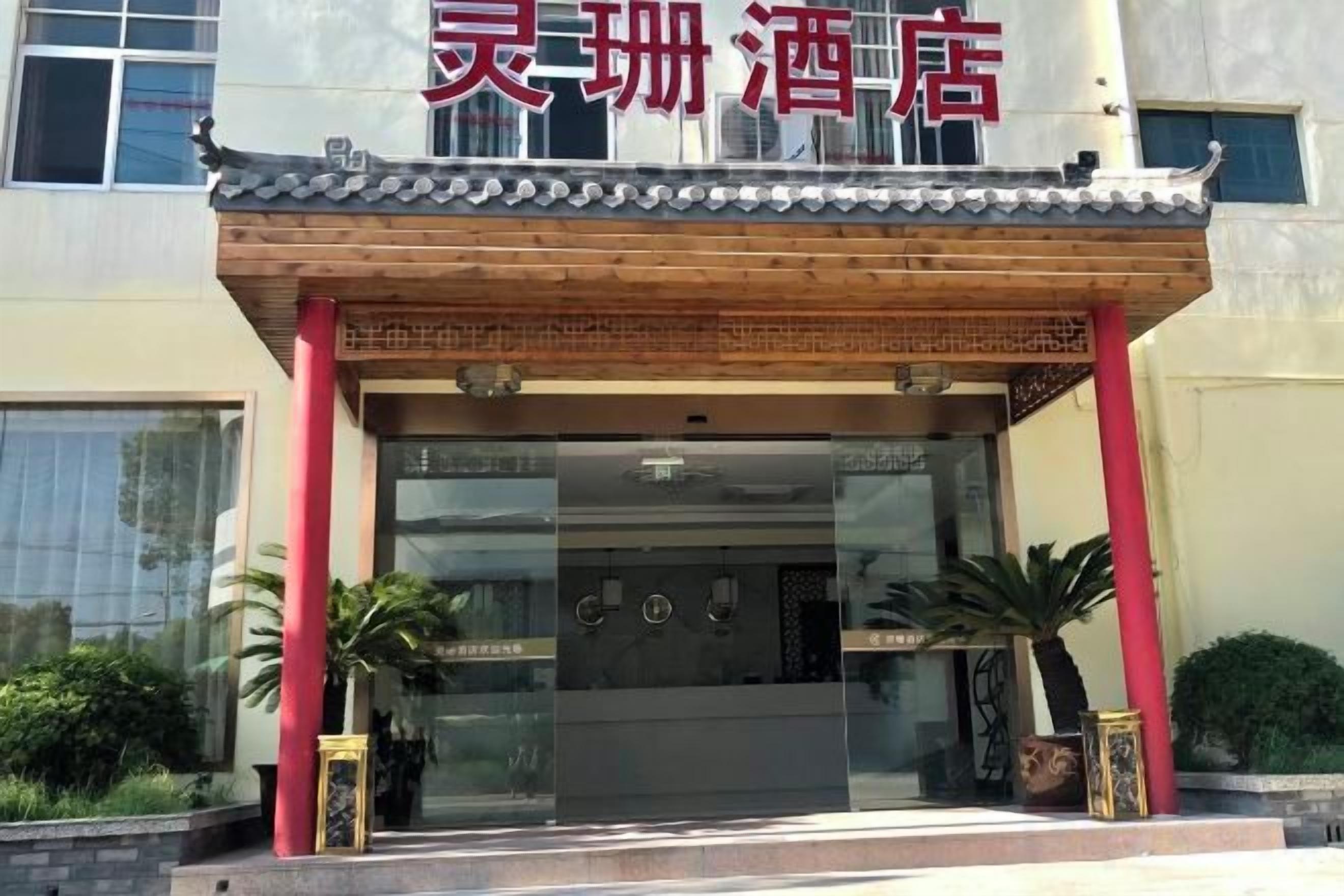 A hotel entrance with a traditional Chinese architectural style, featuring a tiled roof and red pillars.