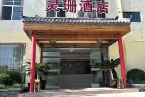 A hotel entrance with a traditional Chinese architectural style, featuring a tiled roof and red pillars. - Lingshan Hotel (Shanghai)