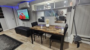 A modern living room with a TV, a dining table, and a sofa. - Lofty Cozy Suite near Nassau Coliseum and Hofstra University (Hempstead)