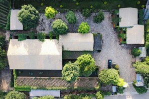 Vista aérea de una propiedad con varias construcciones, áreas verdes y un camino de entrada de grava.