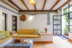 Una habitación con sofá, mesa de centro, techo de madera y un ventanal grande.