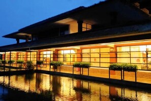 Een gebouw met een reflecterend waterpartij ervoor, grote ramen en een plat dak.
