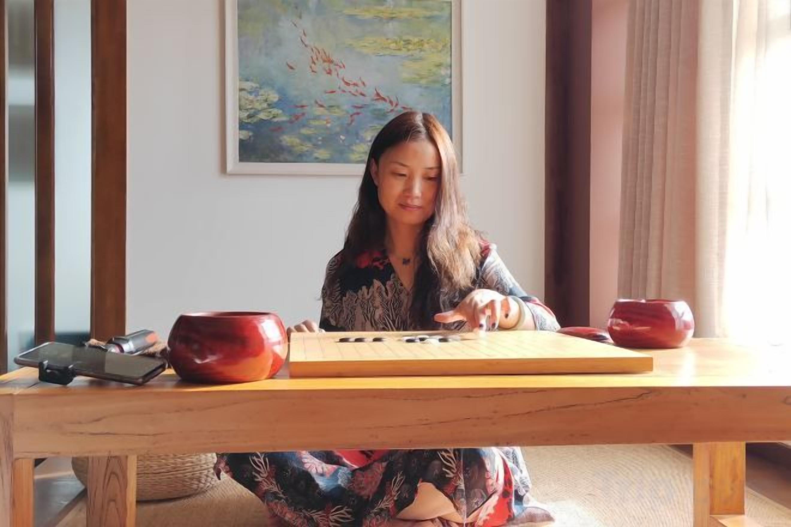 Una persona sentada a una mesa de madera con un teclado y dos cuencos rojos.
