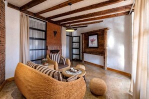 Un salon chaleureux avec des poutres apparentes, une cheminée et des sièges confortables.