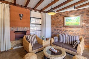 Una habitación acogedora con muebles de mimbre, chimenea y pared de ladrillo.