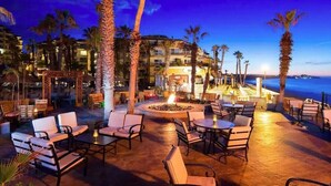 An outdoor patio area with seating and a fire pit, overlooking a coastal view.