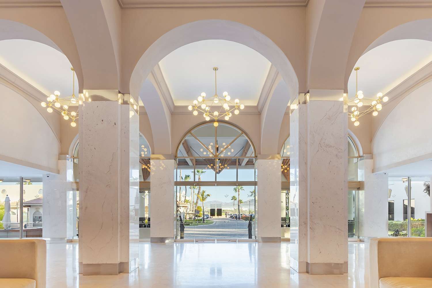 A spacious lobby with high ceilings, marble columns, and a central chandelier.