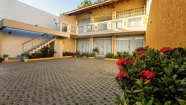 A courtyard with a two-story building, a staircase, and potted plants.