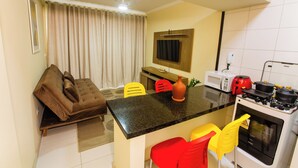 A compact kitchen with a dining area, a microwave, a stove, and a ceiling fan.