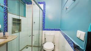 A bathroom with a glass shower enclosure, a white toilet, and a sink with a marble countertop.