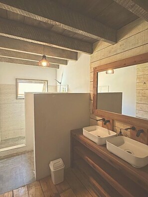 Une salle de bain avec des poutres en bois, deux lavabos, un miroir et une fenêtre.