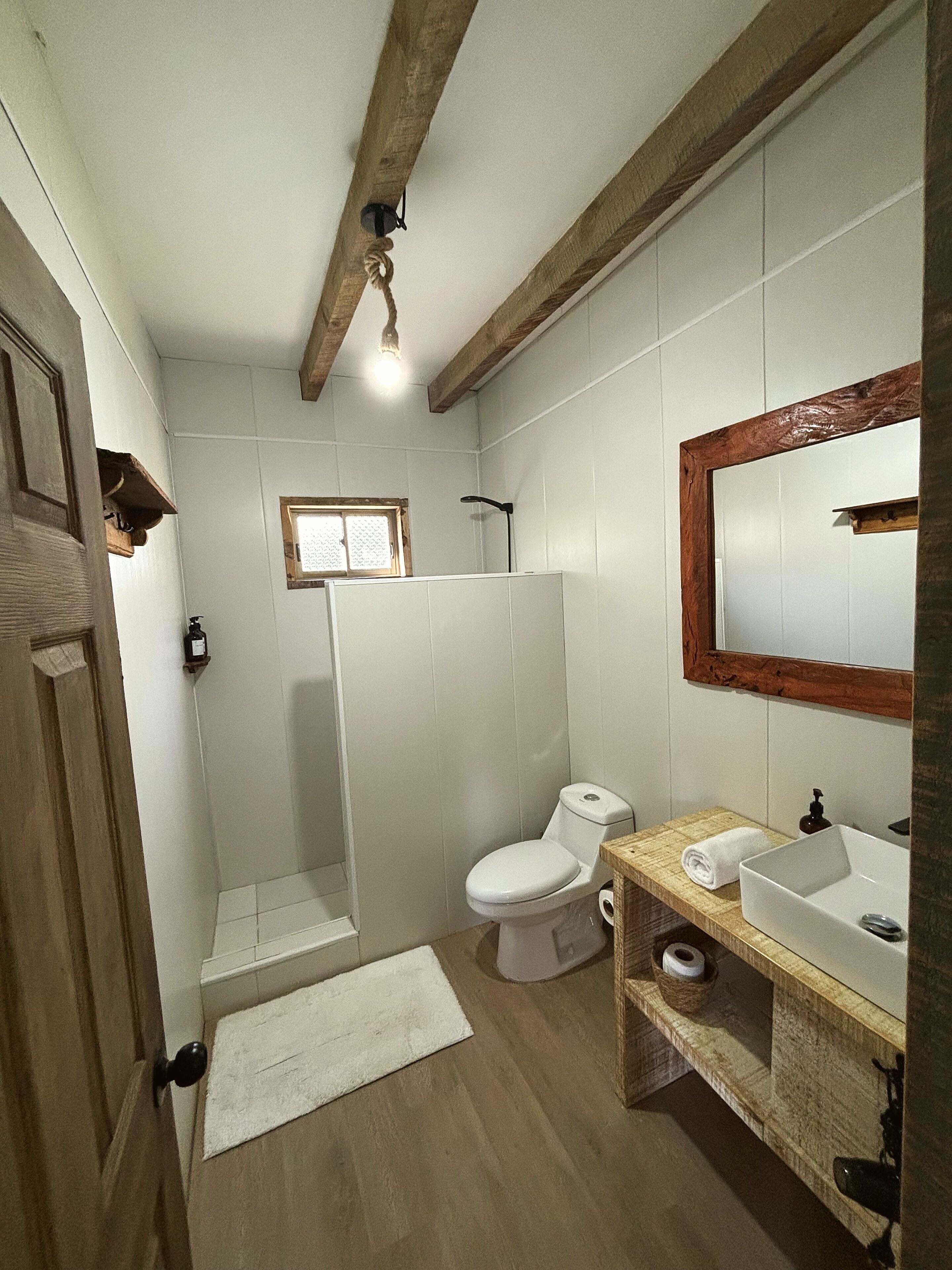Baño con inodoro, lavamanos, ducha y ventana.