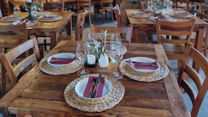 A restaurant with wooden tables and chairs, set with plates, cutlery, and glasses. - Casona El Refugio Casablanca (Casablanca)
