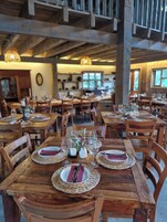 Un restaurante con mesas y sillas de madera, con platos, cubiertos y vasos colocados.