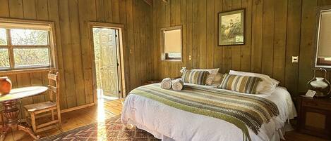 A wooden room with a bed, a table, and a chair.
