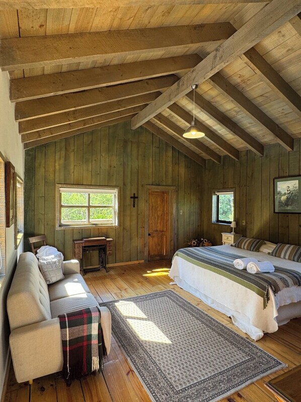 A rustic wooden room with a bed, a sofa, a desk, and a window. - Casona El Refugio Casablanca (Casablanca)