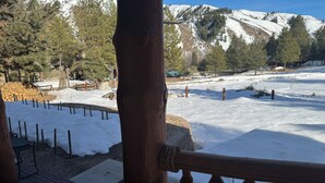 Una terraza de madera con vista a un paisaje nevado y montañas al fondo.