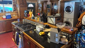Una cocina con gabinetes de madera, estufa, microondas, tostadora, lavamanos y lavadora.