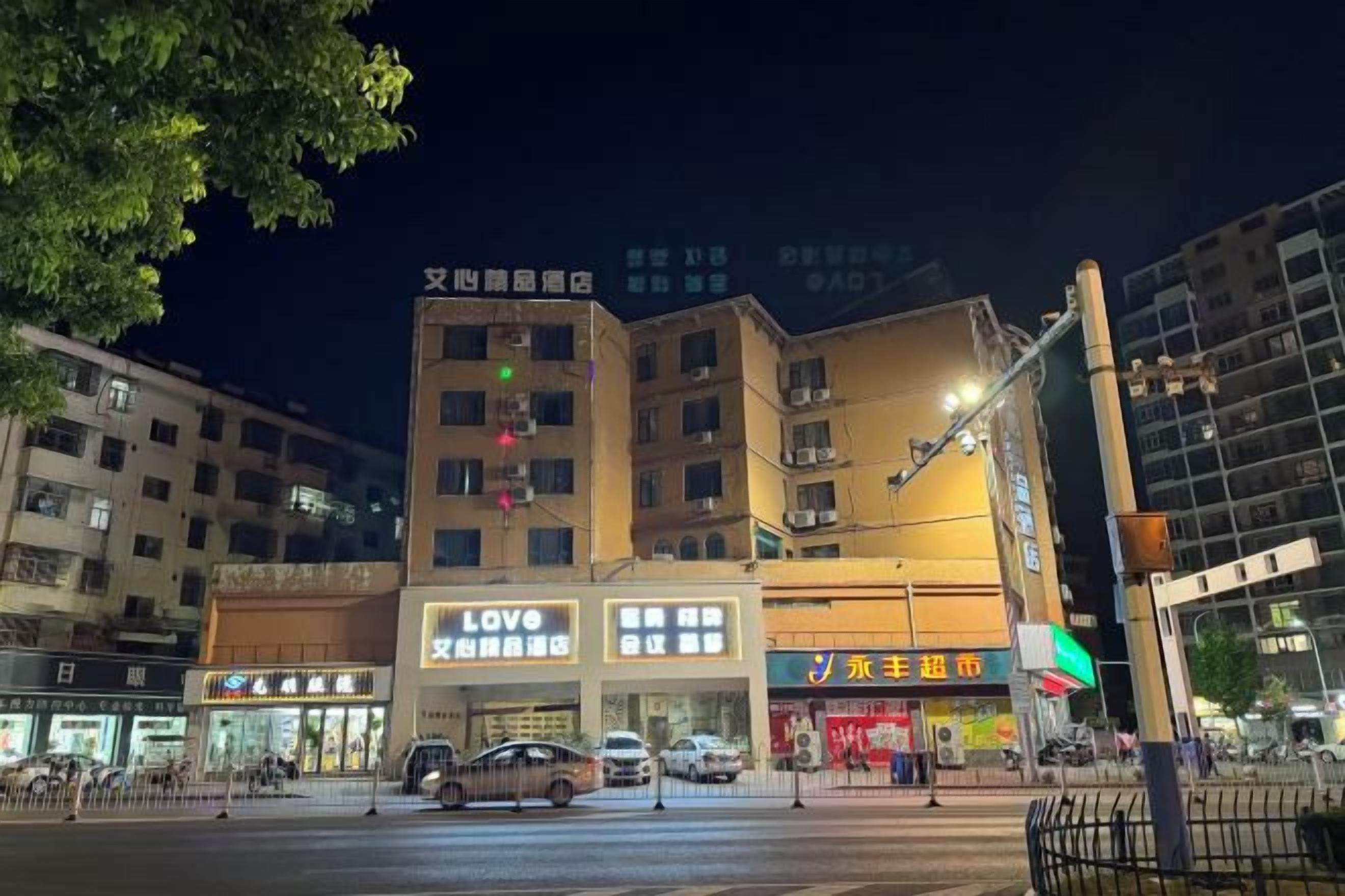 A multi-story building with commercial signage, including a LOVE store and a JYP store, at night.