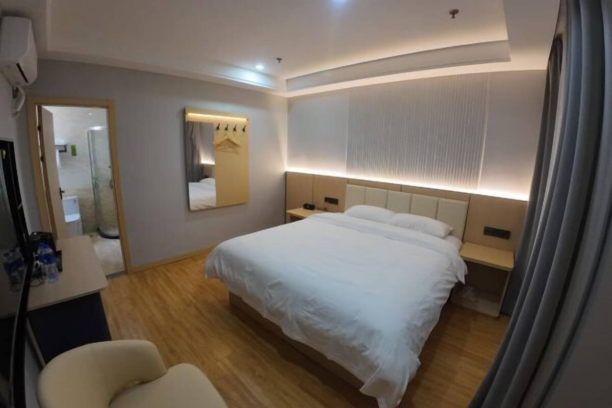 Ein Hotelzimmer mit einem großen Bett, Nachttischen, einem Spiegel und einem Schreibtisch mit Stuhl.