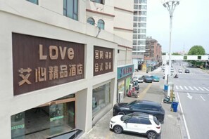 Ein Gebäude mit einem auffälligen 'Love'-Schild, ein Schaufenster und abgestellte Autos.