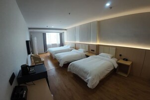 Una habitación de hotel con dos camas, un escritorio, una silla, un televisor y una ventana con cortinas.