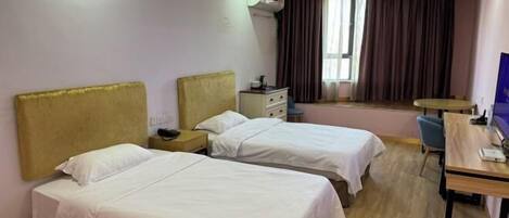 Habitación de hotel con dos camas individuales, un escritorio, una silla, una mesita y una ventana con cortinas.