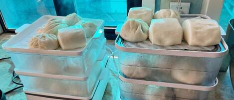 Two food containers with food items, possibly dumplings, on a countertop.