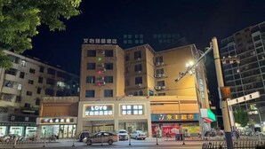 A multi-story building with various shops on the ground floor, including a visible 'LOVE' store.
