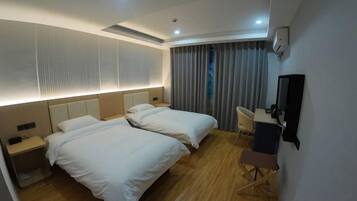 A hotel room with two beds, a desk, a chair, a TV, and a window with curtains.