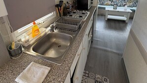 Une cuisine compacte équipée d’un four à micro-ondes, d’un évier et d’une cuisinière, donnant sur un coin repas avec une fenêtre.