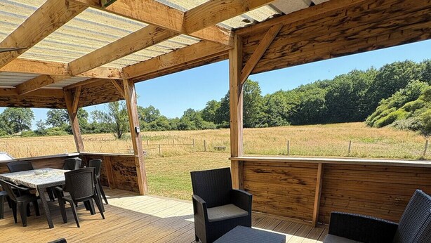 Une terrasse extérieure en bois, avec une table et des chaises, entourée de meubles en osier.