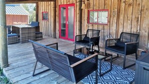 Un patio al aire libre con mobiliario de mimbre, una puerta roja y una terraza de madera.