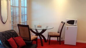 A living room with a black leather sofa, two chairs, a glass coffee table, and a white refrigerator. - Safe & beautiful new studio in charming Sherman Oaks neighborhood (Los Angeles)