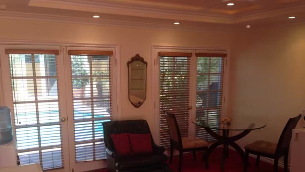 A room with a red carpet, a black leather chair with red cushions, a small table, and a mirror on the wall. - Safe & beautiful new studio in charming Sherman Oaks neighborhood (Los Angeles)