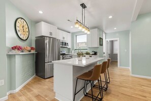 A modern kitchen with white cabinets, stainless steel appliances, and a central island with bar stools. - By PPG,Duquesne,Mercy |Exquisite, New |Free Parkin (Pittsburgh)