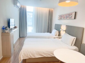 A hotel room with two beds, a desk with a television, a coffee maker, and a painting on the wall. - Hanting Hotel Shanghai Anting Car City (Shanghai)