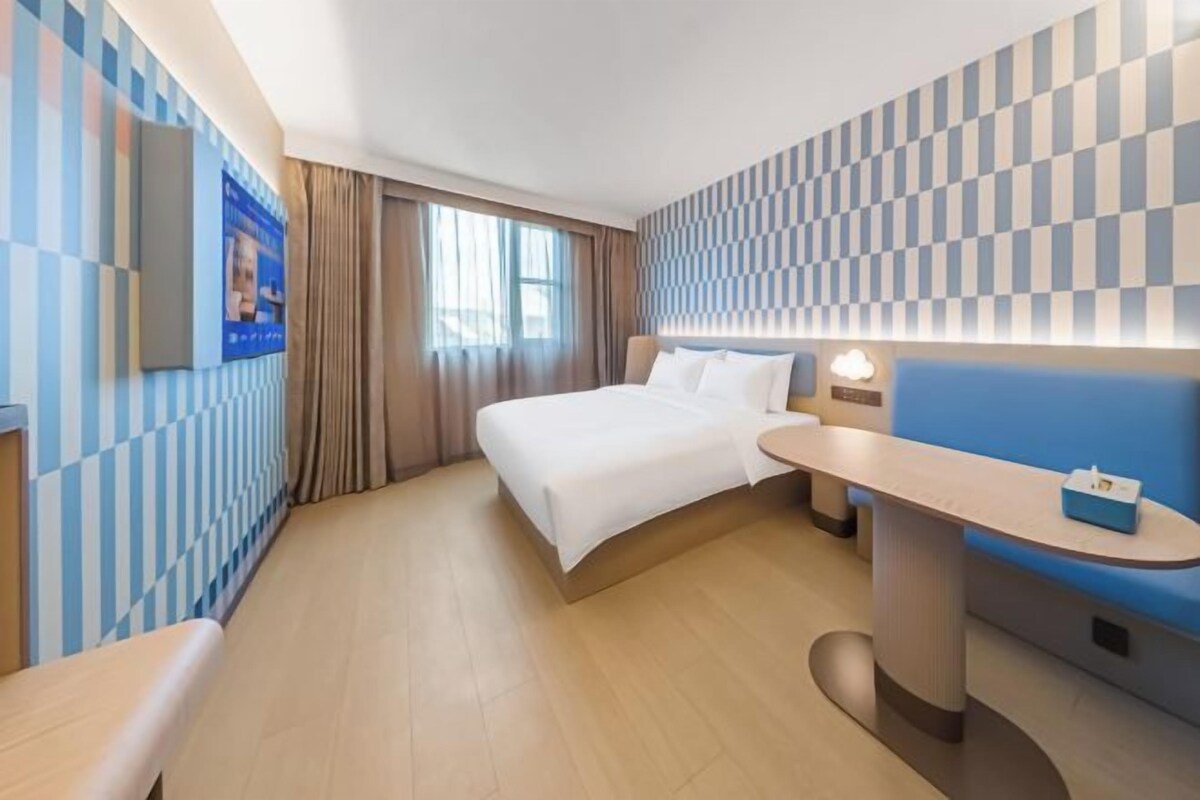 A hotel room with a bed, bedside table, and a seating area.