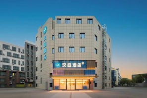 A hotel with a modern facade, multiple floors, and a prominent entrance with illuminated signage. - HanTing Hotel (Shanghai Anting Auto City) (Shanghai)