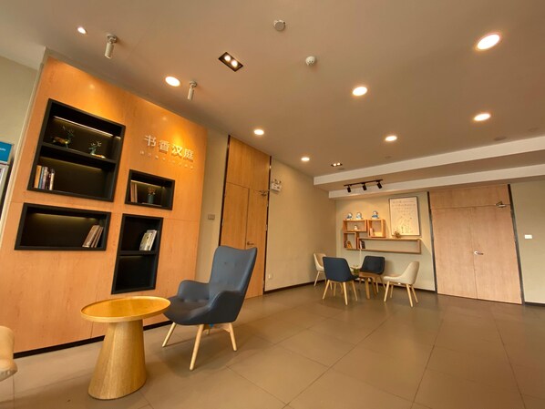 A reception area with a wooden wall, bookshelves, a reception desk, and seating.