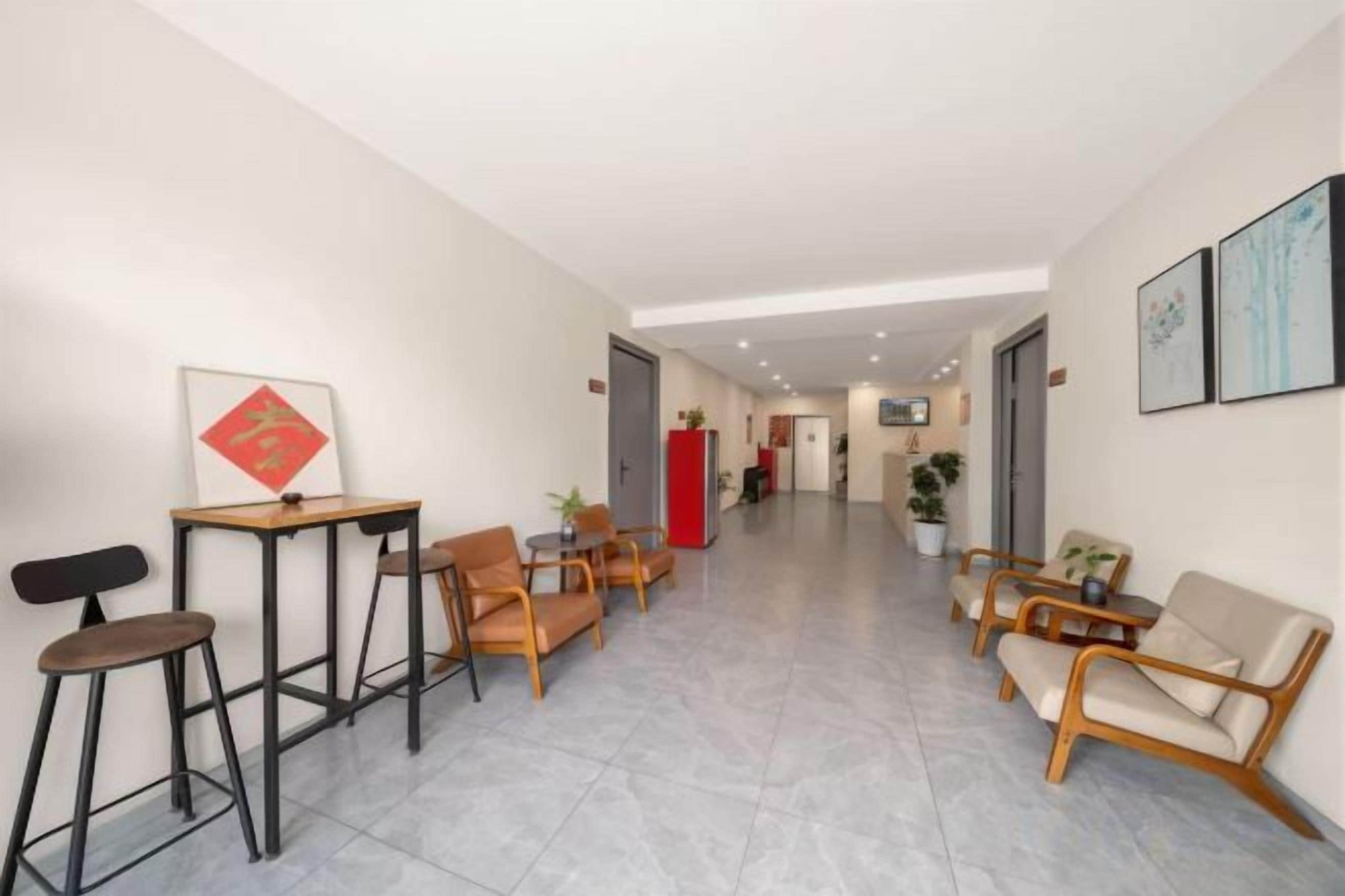 A hotel lobby with a reception desk, seating area, and a hallway leading to other rooms.