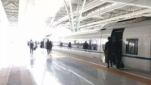 A train station platform with a train, passengers, and a covered roof structure. - Pebble Motel (Shanghai Beidi Road) (Shanghai)