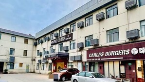 A building with multiple storefronts, including a restaurant named "Carly's Burgers." - Pebble Motel (Shanghai Beidi Road) (Shanghai)